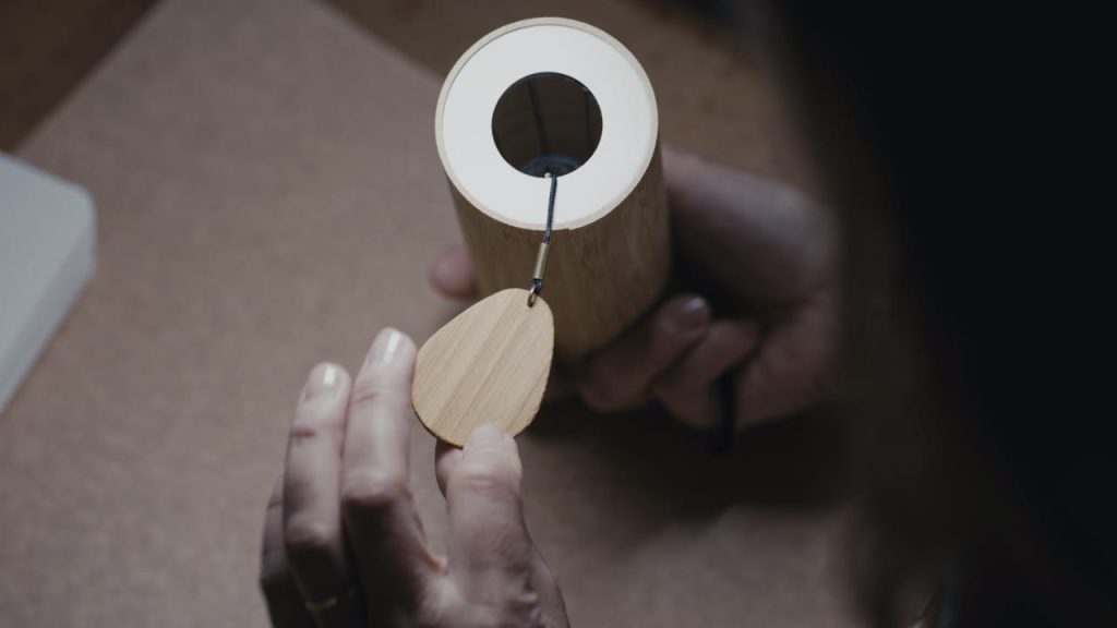 Une main tient la masselotte d’un carillon Koshi